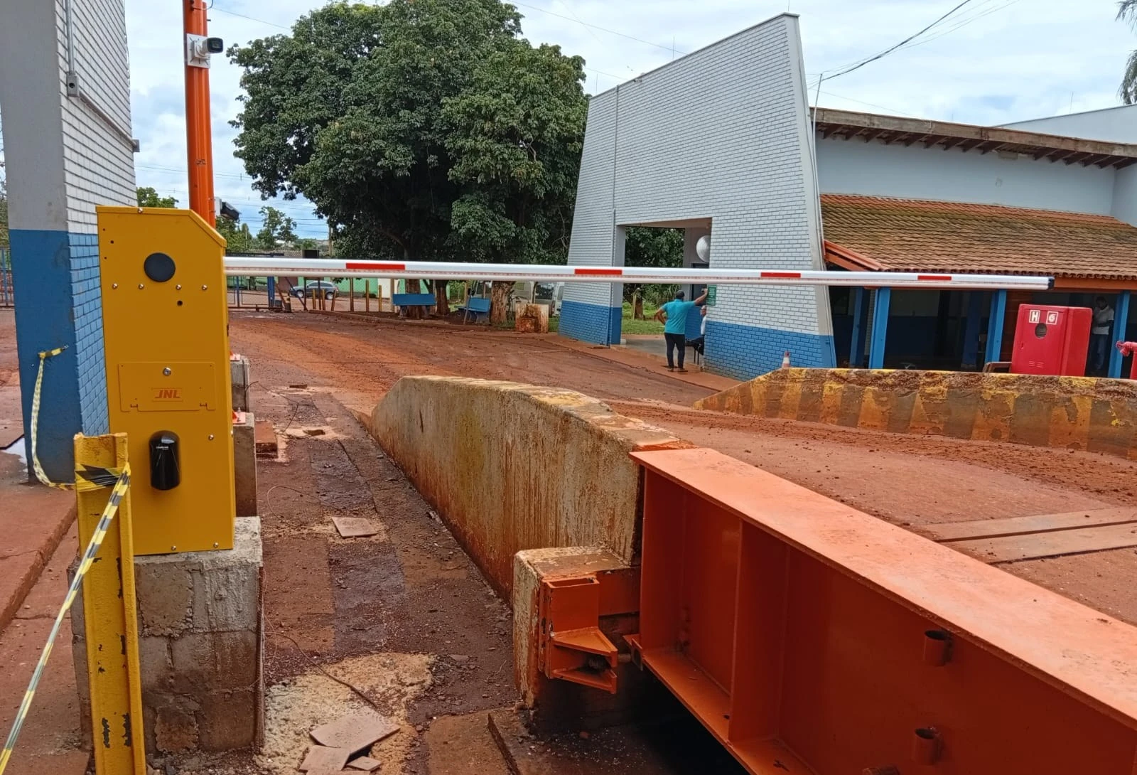 Barrera amarilla y tótem en la cabecera de una báscula camionera metálica, en obra de JNL