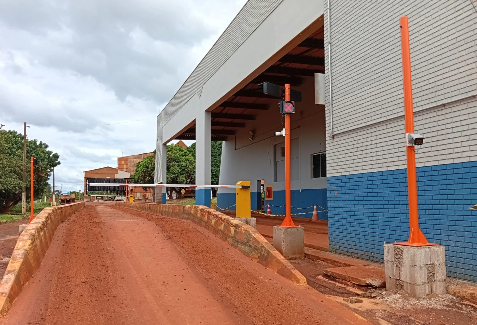 Postes naranjas con cámara, semáforo y display remoto al lado de la pista de pesaje, en obra de JNL